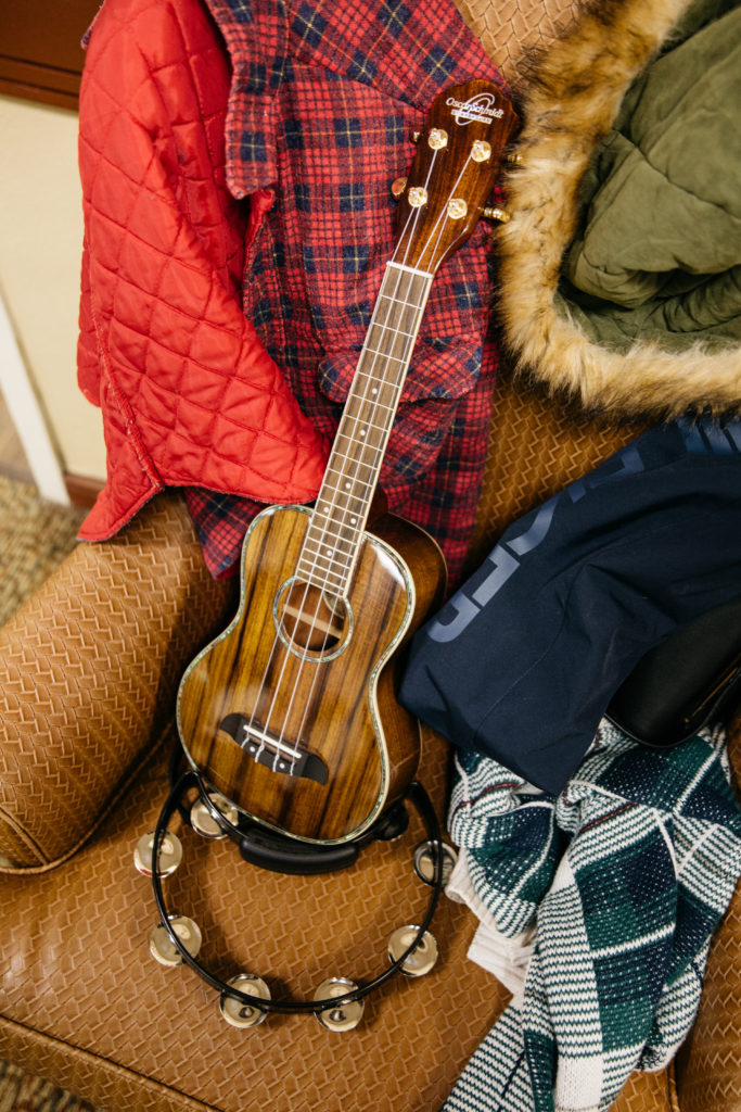 Ukulele on an armchair surrounded by jackets