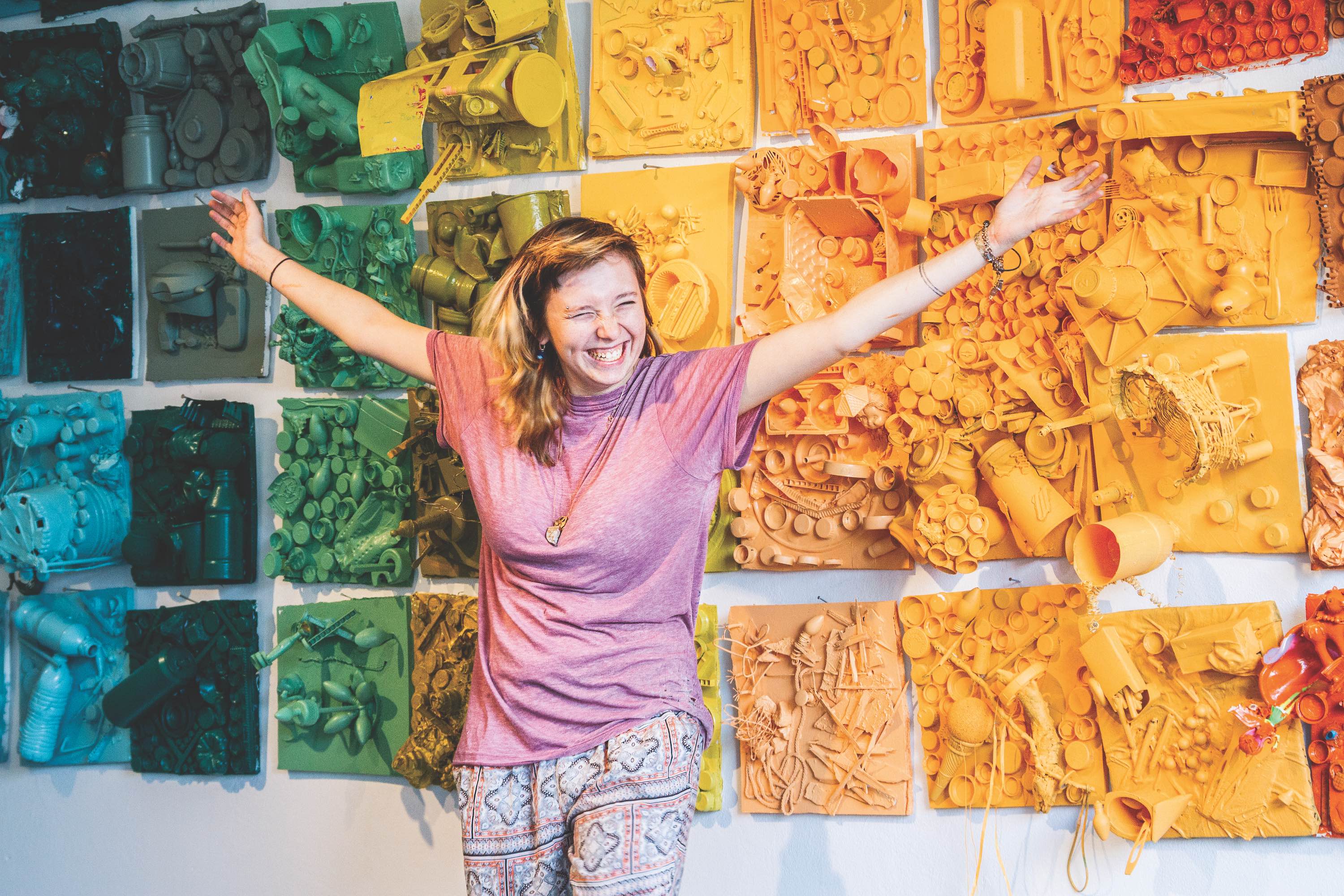 woman smiling in front of multicolored art pieces