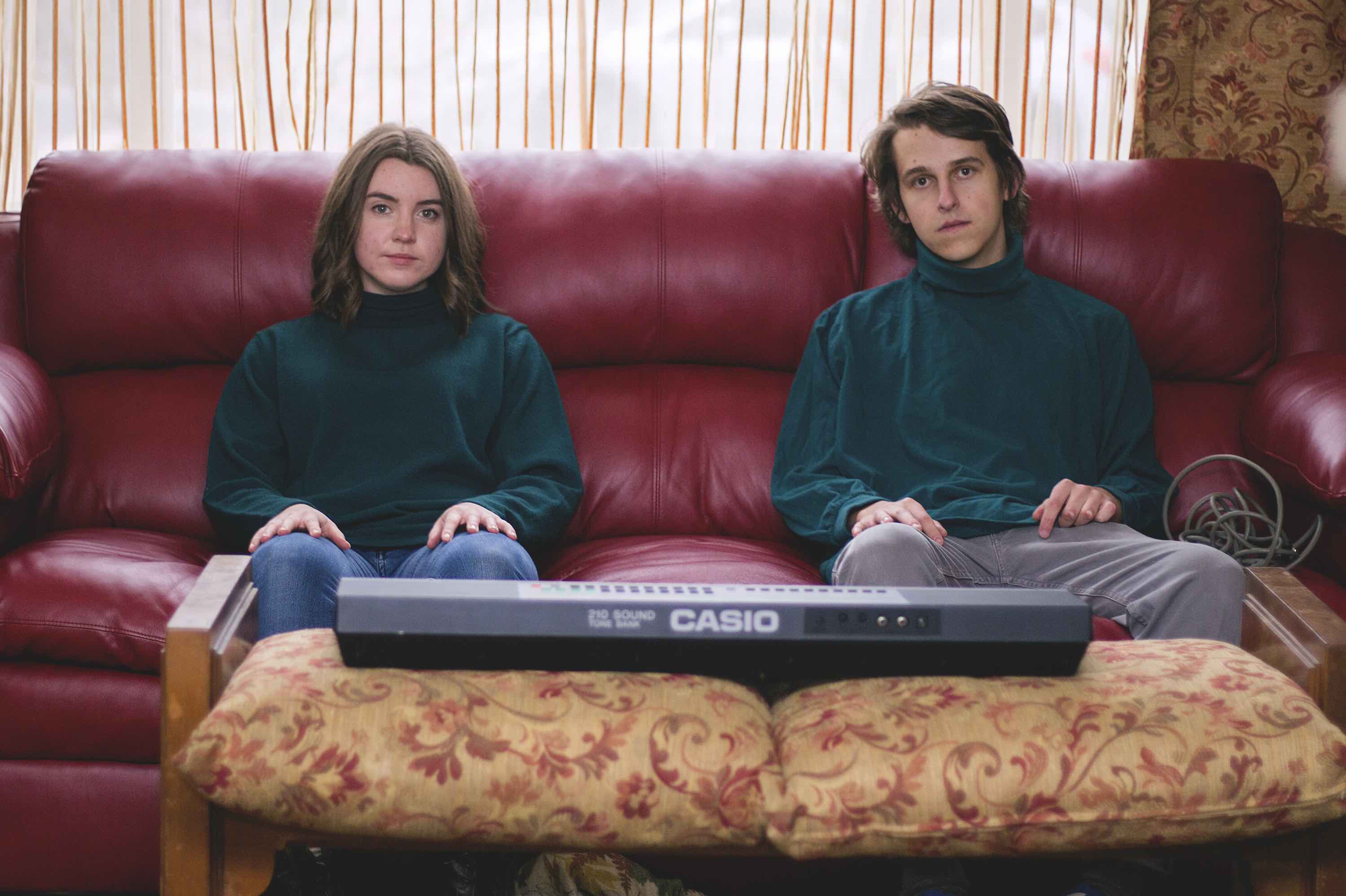 man and woman sitting on a couch with a keyboard in front of them