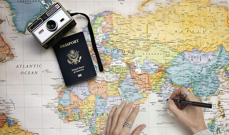 Person Drawing a Map with a Camera and Passport on the Side