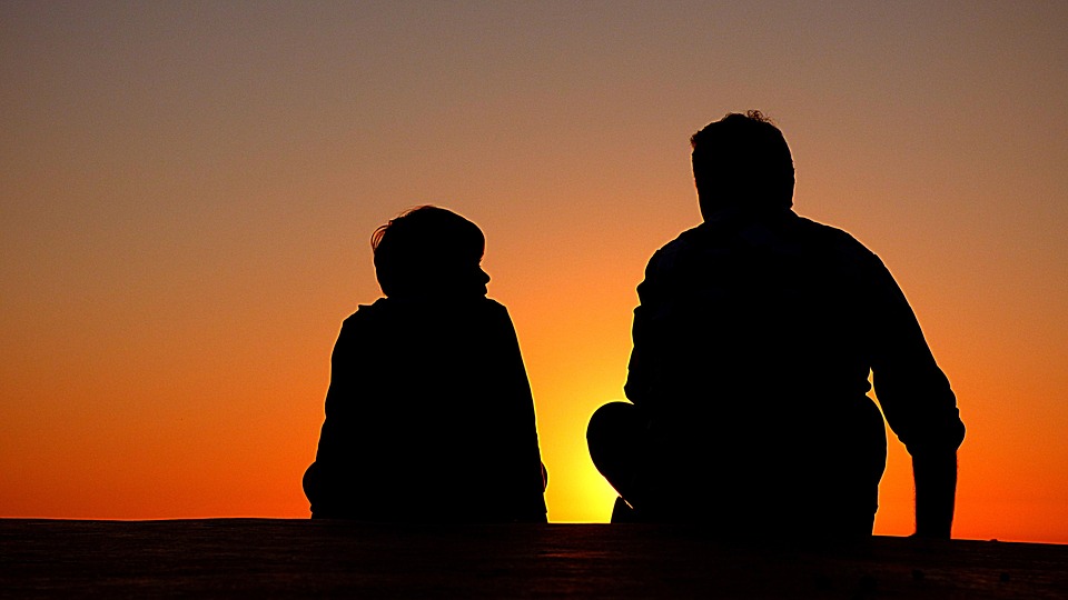 silhouette of a father and son sitting side by side